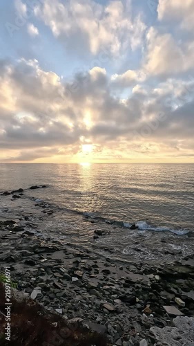 Vertical video of a panoramic horizon line of an breathtaking sky at sunrise or sunset with the sunbeams through clouds over the Mediterranean Sea from the coast
