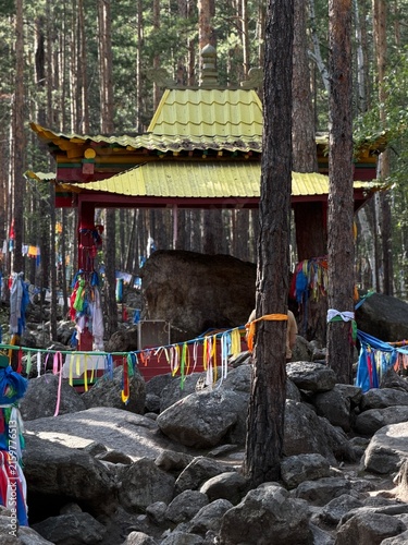 Obraz na płótnie Colorful prayer flags adorn a small traditional shrine with a yellow roof surrou