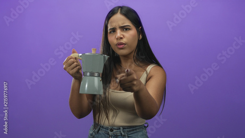 Принти на полотні Woman holding moka pot and pointing finger at camera with stern expression against purple backdrop in studio; assertion warning