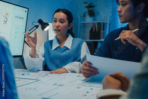 Asia businesspeople presentation sales meeting plan statistics brainstorm and work with paperwork around table in office conference room at night. Business finance partner strategy investment success.