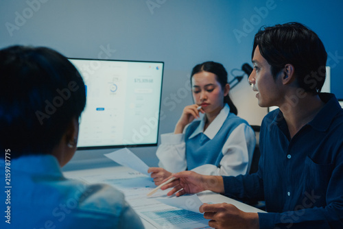 Asia businesspeople presentation sales meeting plan statistics brainstorm and work with paperwork around table in office conference room at night. Business finance partner strategy investment success.