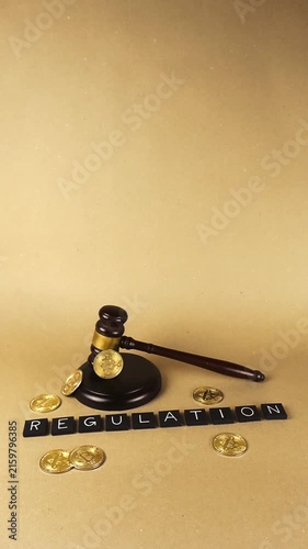 Conceptual scene on a light brown background with the word regulation spelled in tiles, surrounded by golden bitcoin coins and a judge's gavel, representing the legal aspects of cryptocurrency