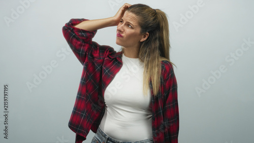 Fotografie Woman touching forehead with hand, wearing red plaid shirt and white t shirt, looking perplexed in studio; frustration doubt