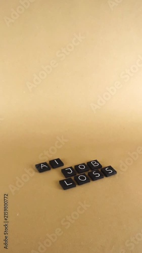 Conceptual video showing the phrase AI job loss spelled out with black letter tiles on a plain brown background, representing the impact of technology and automation on employment