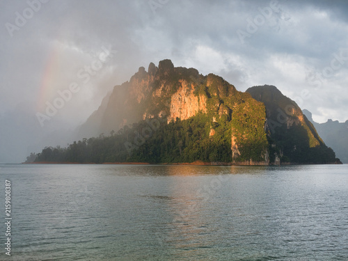 Ratchaprapha Dam in the morning featuring sunlight and mist amidst khao sok national park in surat thani province thailand where towering limestone cliffs rise from the freshwater reservoir.