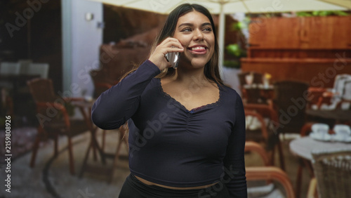 Photography Woman holding phone to ear, smiling with closed eyes and grinning at street cafe; contentment casual chat