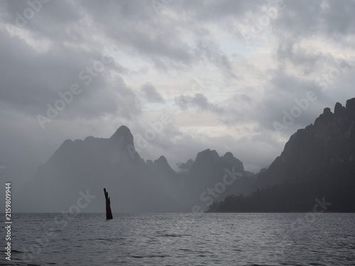 Ratchaprapha Dam in the morning featuring sunlight and mist amidst khao sok national park in surat thani province thailand where towering limestone cliffs rise from the freshwater reservoir.