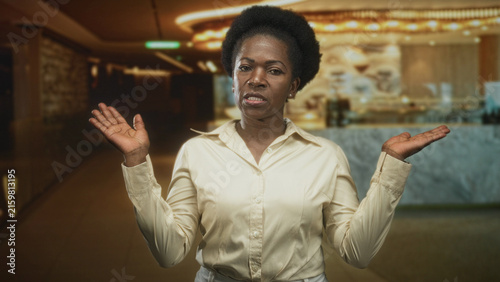 Fotografie Woman holding both palms up in a shrug gesture at a marble reception desk inside a building; uncertainty