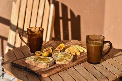 Outdoor breakfast with bread and honey, cheese, figs and coffee