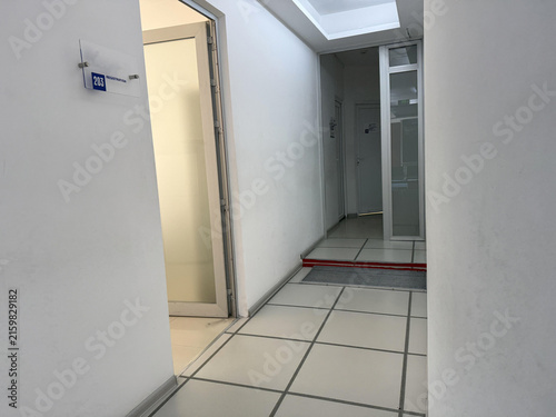 A waiting area shows a brown bench along the wall a trash can beside it and two doors leading to different rooms.