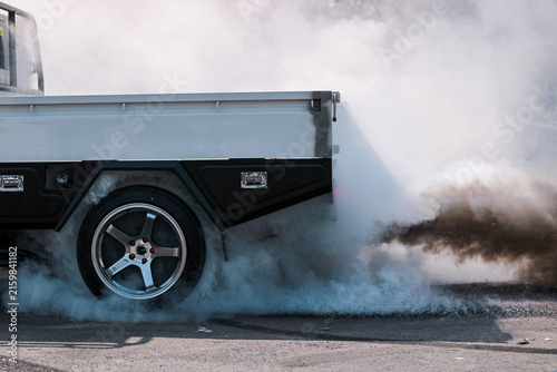 Modified pickup truck performing a dramatic burnout on asphalt, creating thick tire smoke and a dynamic automotive scene with space for advertising copy.