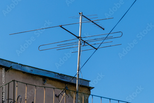 Fotografía Metal antenna stands atop a building roof
