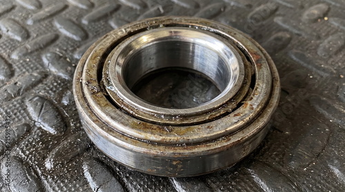 Used dirty automotive steel bearing with rust and grease resting on a dark textured surface