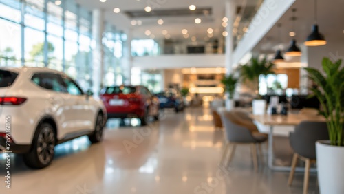 wide angle blurred interior of a modern car dealership showroom with new vehicles and customer lounge.