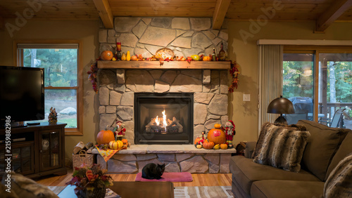 Cozy living room with stone fireplace decorated for autumn and Thanksgiving holidays.