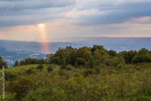 Картината върху платно A mountain range covered in the wild woods illuminated by the golden light of the setting sun