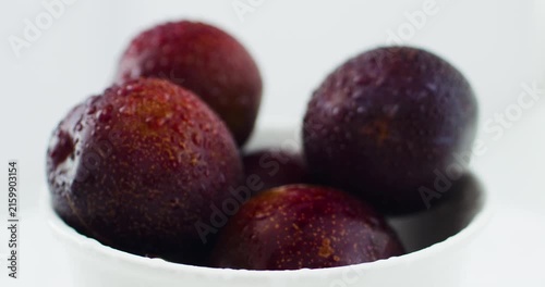 Ripe, juicy plums in a snow-white bowl. Fruits and time of harvesting. Juicy plums sprinkled with water close up.