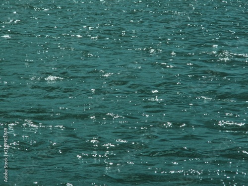 Sunlight sparkles across gently rippling turquoise water surface 