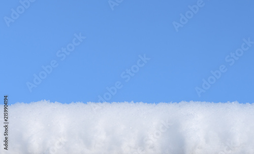 Fresh sparkling snow close-up in front of bright blue sky perfect as a winter season background