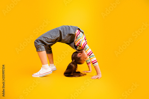 фотографія Young girl doing a backbend bridge pose on a bright yellow background showing fl