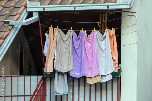 Wet towels and other clothes drying outside on a string in house balcony