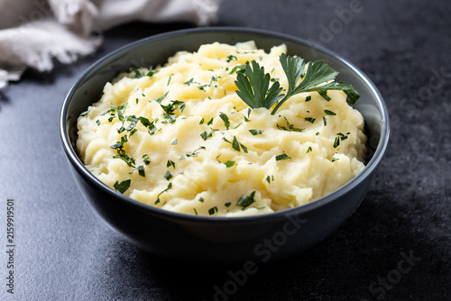 Foto Creamy mashed potatoes with fresh parsley on black background
