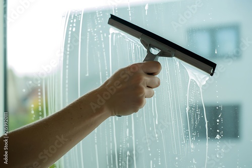 Human hand cleaning soapy window glass squeegee rubber wiper photo