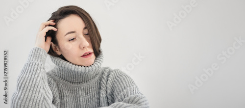 фотографія Sad woman in a gray knitted turtleneck looks withdrawn and thoughtful against a neutral background with generous copy space