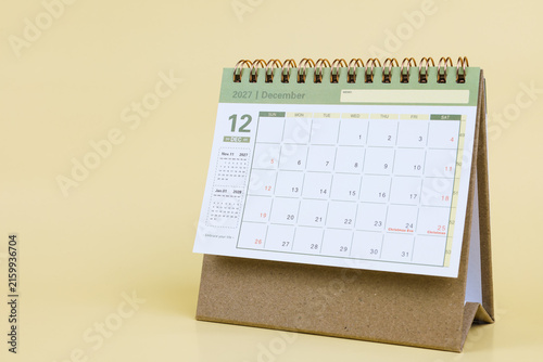Desk calendar standing on a light yellow background displaying December 2027, ideal for planning, schedule management, and time organization.