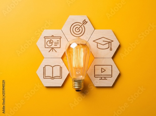 Light Bulb with Wooden Hexagon Tiles Featuring Education and Business Icons on Yellow Background