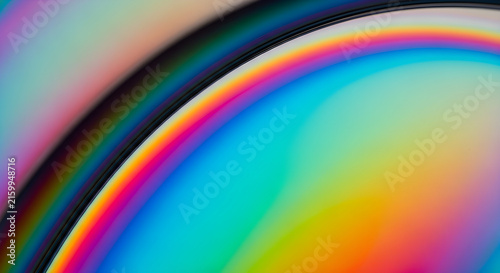 Abstract Macro Photography Featuring Vibrant Iridescent Rainbow Light Refractions on a Curved Metallic Surface with Soft Gradient Transitions