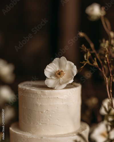 Elegant wedding cake with floral decoration on rustic table.
