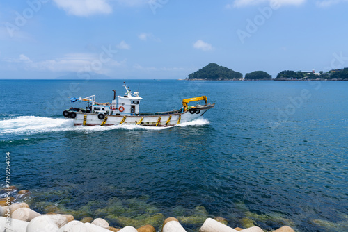 Aquaculture Fishing Boat with Yellow Crane Cruising Past Tetrapod Jetty