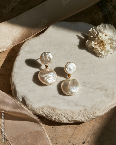 Vintage pearl drop earrings on marble surface with ribbon.