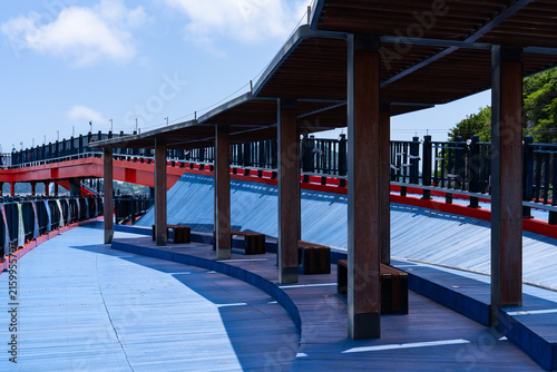 Covered Wooden Rest Area with Benches on Blue Coastal Boardwalk