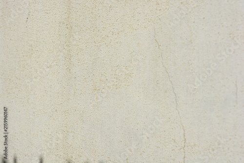 Construction and renovation work, plastering load-bearing street walls in sunlight. The white walls are coated with rough street primer with long micro-cracks throughout the surface and background.