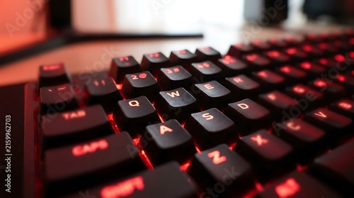 Close-up of mechanical gaming keyboard with red backlight illumination and wasd keys, keyboard