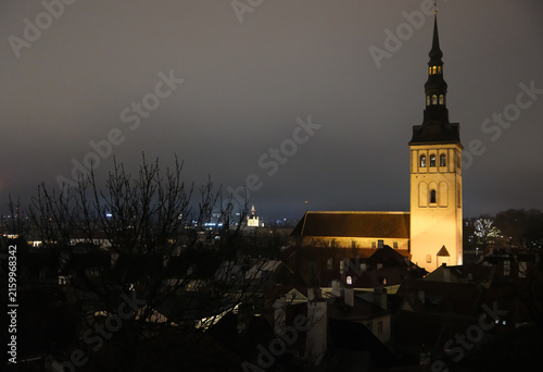St. Nicholas Church at night in Tallinn, illuminated Gothic church tower above the rooftops of Tallinn Old Town 
