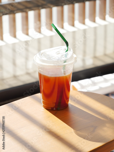 Iced Americano Coffee in Clear Plastic Cup on Sunlit Wooden Table