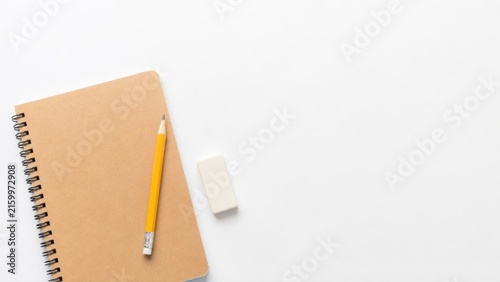 Spiral notebook with yellow pencil and eraser on white background with large copy space