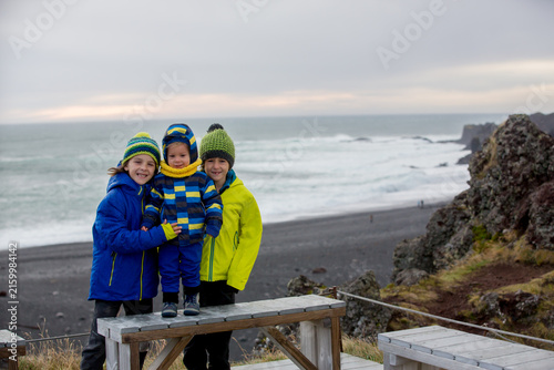 Kids standing on shore of the ocean, beautiful nature in Snaefellsjokull National Park in Iceland, autumntime