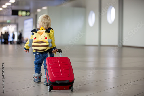 Cute  baby boy waiting boarding to flight in airport transit hall near departure gate. Active family lifestyle travel by air with child