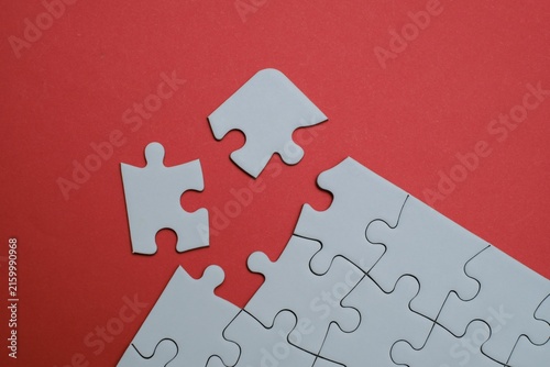 Fotografie White jigsaw puzzle with missing pieces separated on a red background