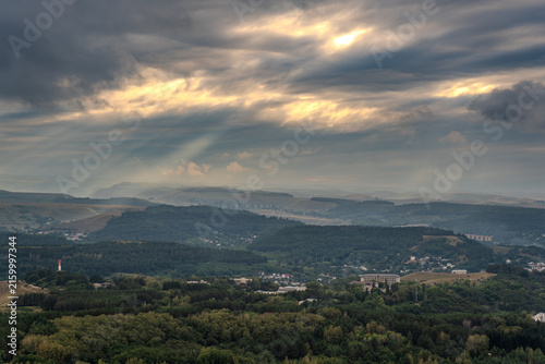 Картината върху платно A mountain range covered in the wild woods illuminated by the golden light of the setting sun