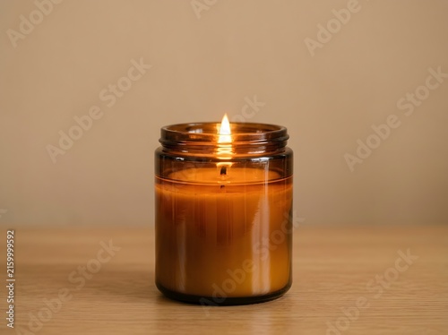 Cozy amber glass jar with a burning scented candle on a wooden table