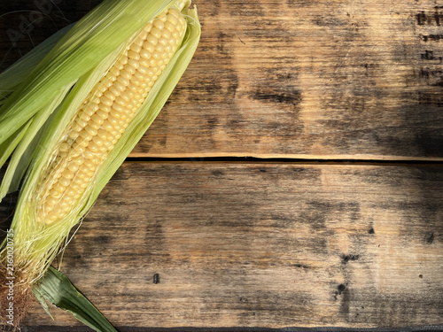 Horizontal flat lay of fresh sweet corn on a rustic wooden background with copy space