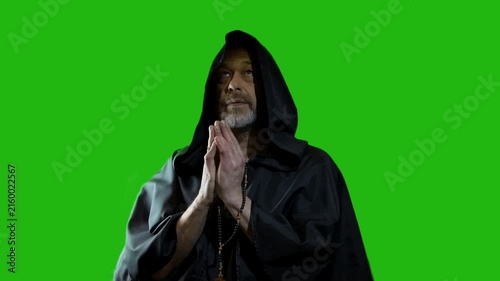 Hooded monk prays, raises his gaze upward, then bows in silence
