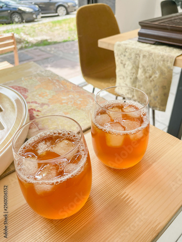 Foto Two iced tea glasses on a wooden table inside a bright cafe, sunlight streaming