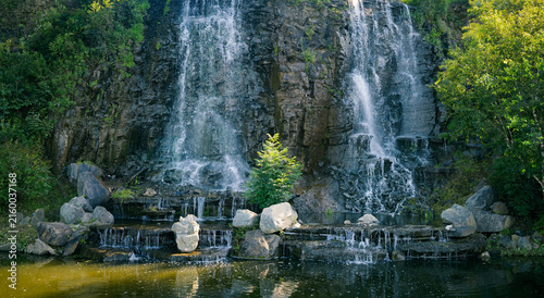 Scenic waterfall cascading over rocky cliff into tranquil pond.