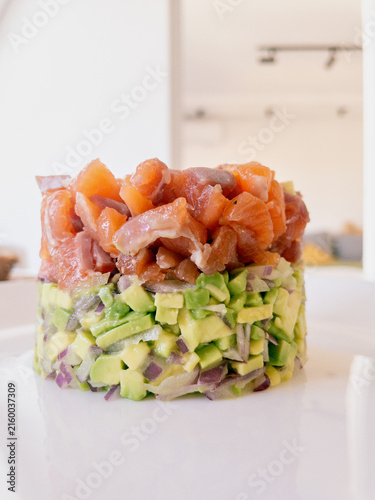 Foto Salmon and avocado layered tower on a clean plate with onion accents, showcasing